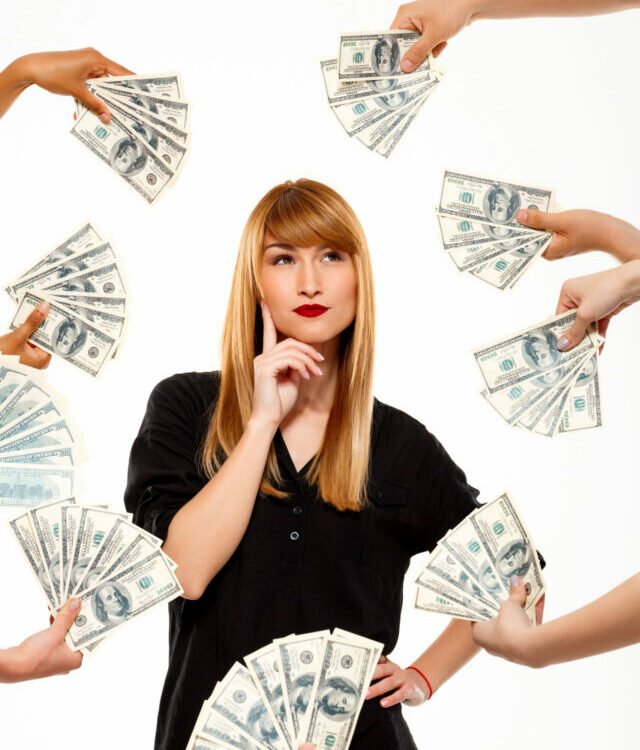 Portrait of successful businesswoman among money over white background.